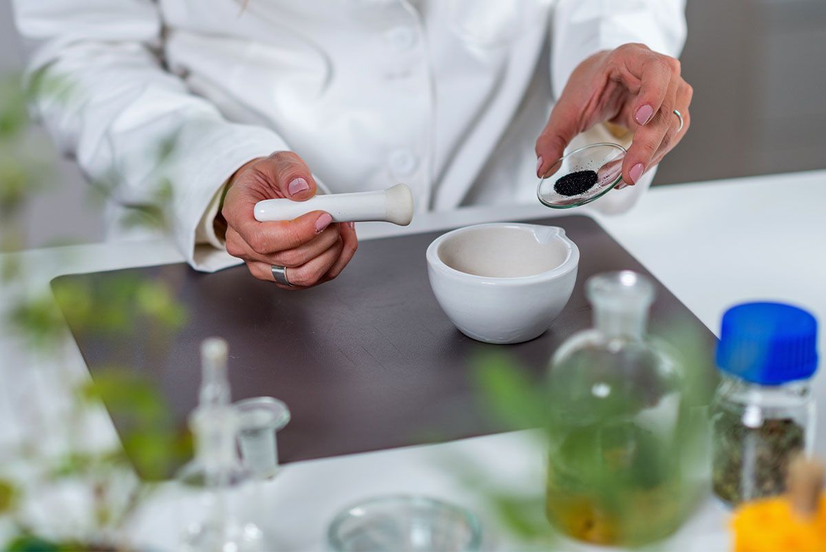 ubereitung einer naturheilkundlichen Arznei mit Mörser und Kräutern in der Apotheke