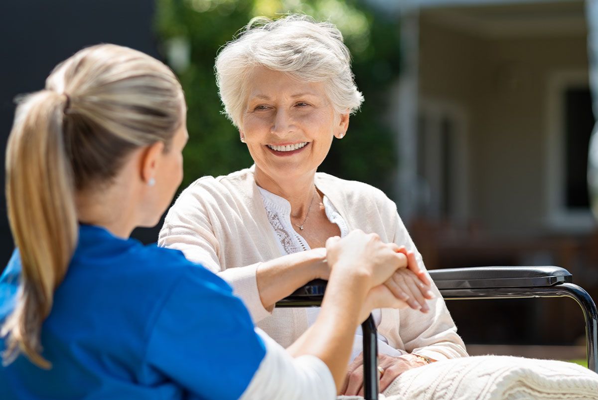Pflegekraft spricht mit einer älteren Frau im Rollstuhl – Apotheke mit Schwerpunkt Senioren- und Pflegeberatung